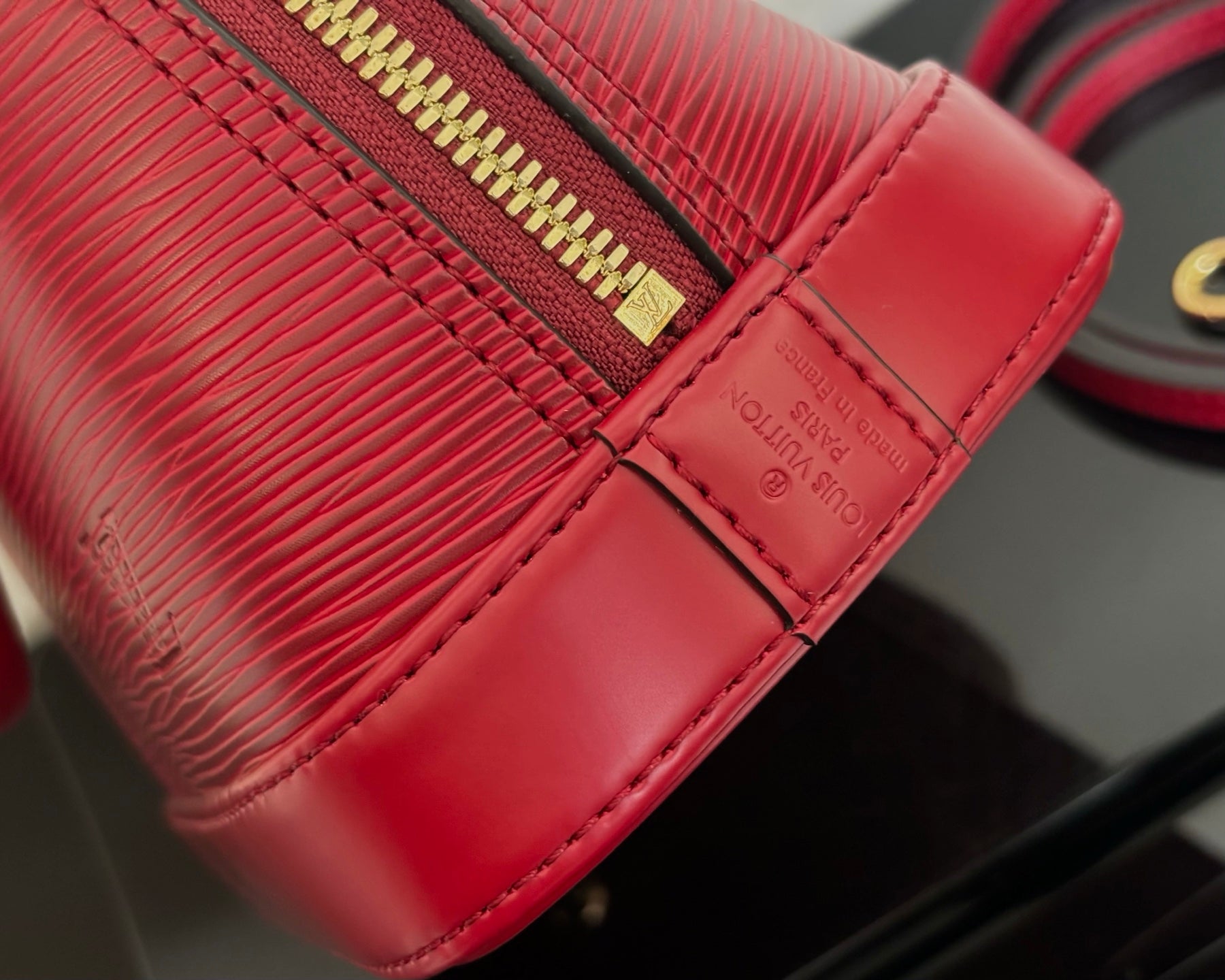 Louis Vuitton red handbag close-up of textured leather and stitched seam