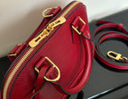Louis Vuitton red handbag side detail with gold-tone zipper pull and D-ring