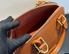 Tan leather handbag interior view with zip top and ring clasp on front