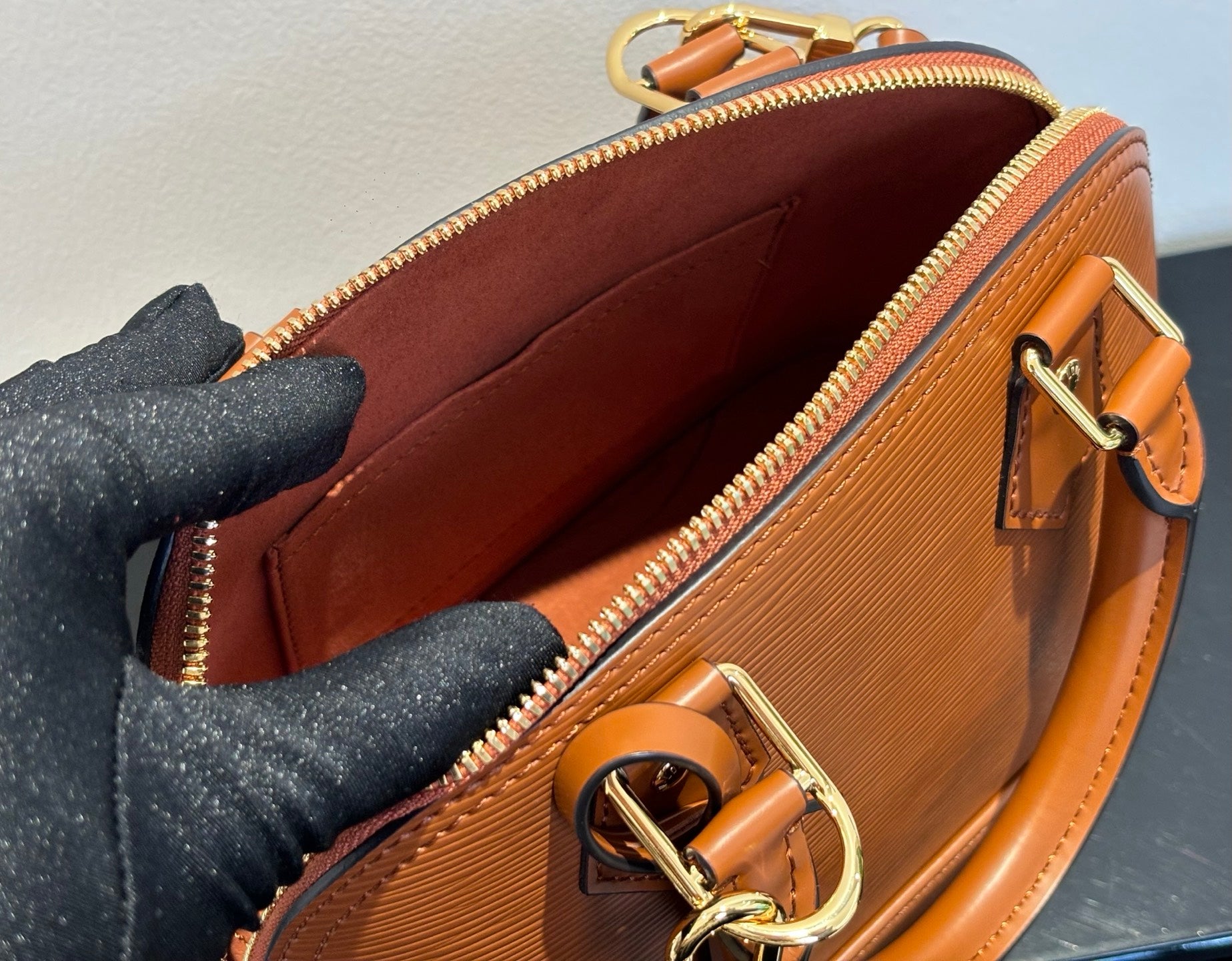 Tan leather handbag interior view with zip top and ring clasp on front