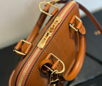 Side view of tan leather handbag with zip pocket and gold clasp detail, crossbody strap