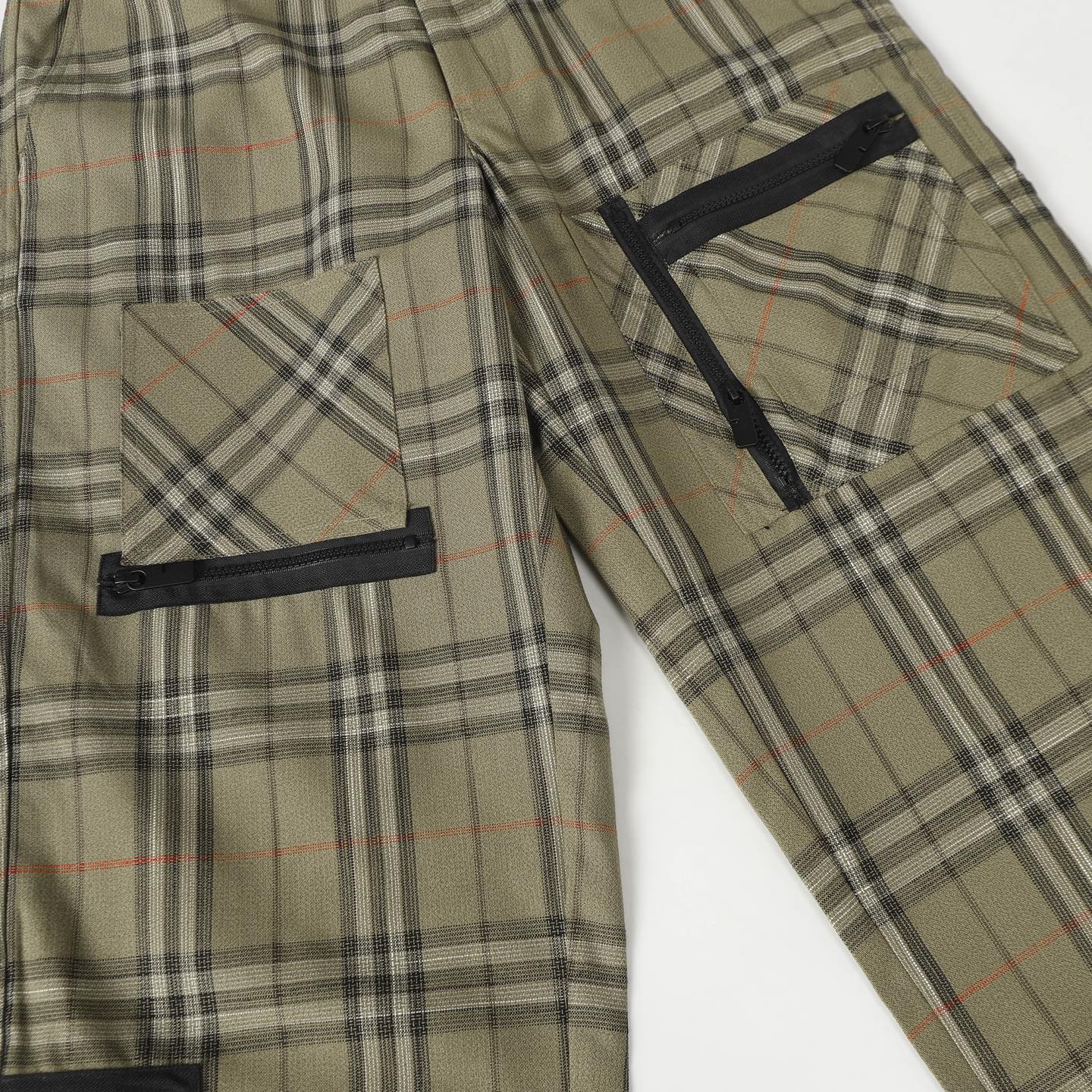 Olive plaid pants with black side pockets and drawstring hem strap
