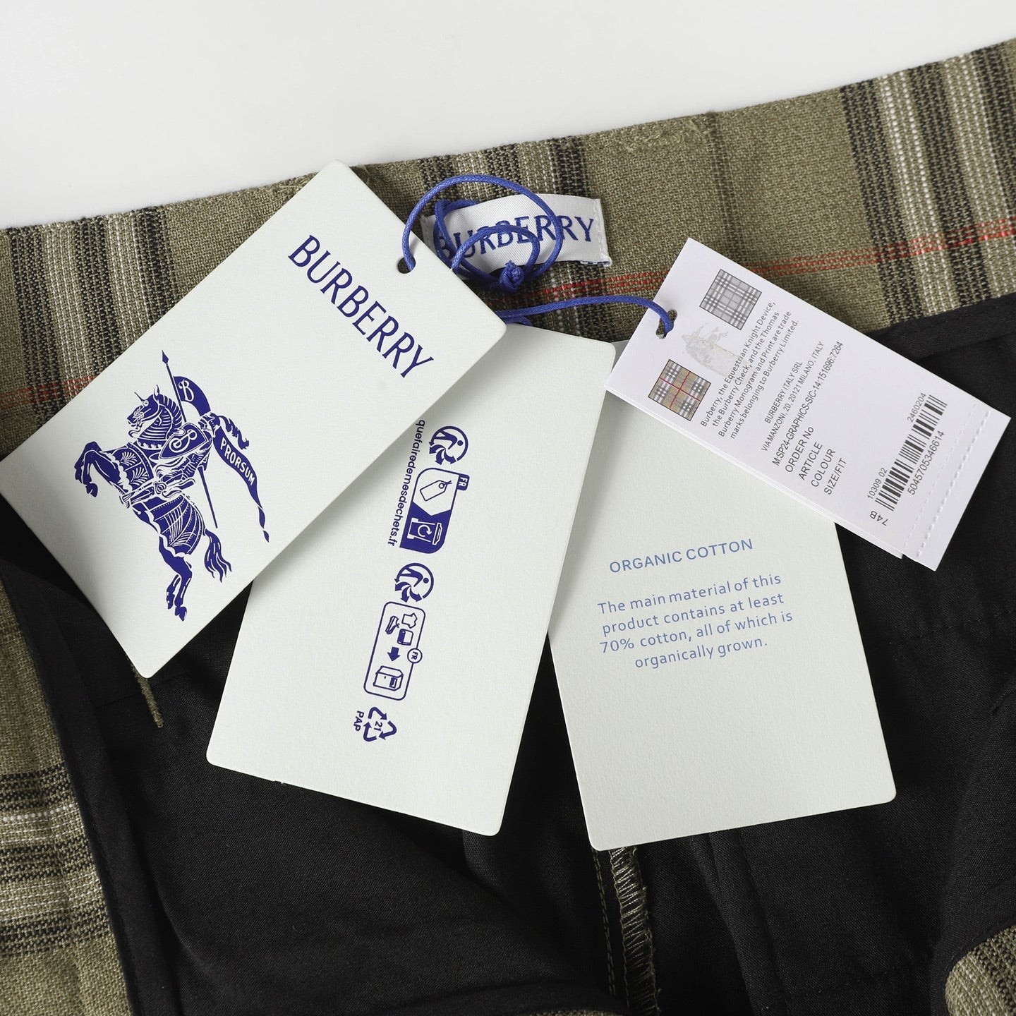Inside view of olive plaid pants with attached tag and fabric information labels