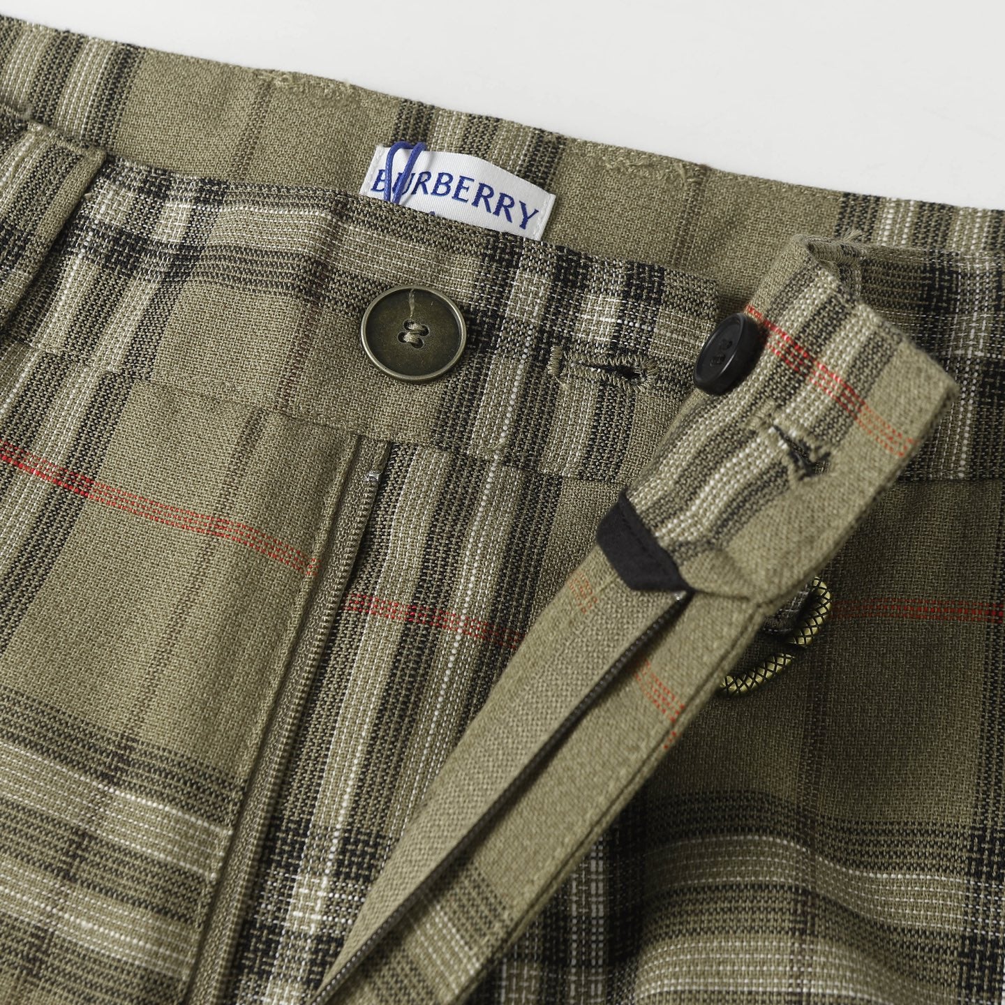 Waistband of plaid pants with button closure and stitched drawstring channel
