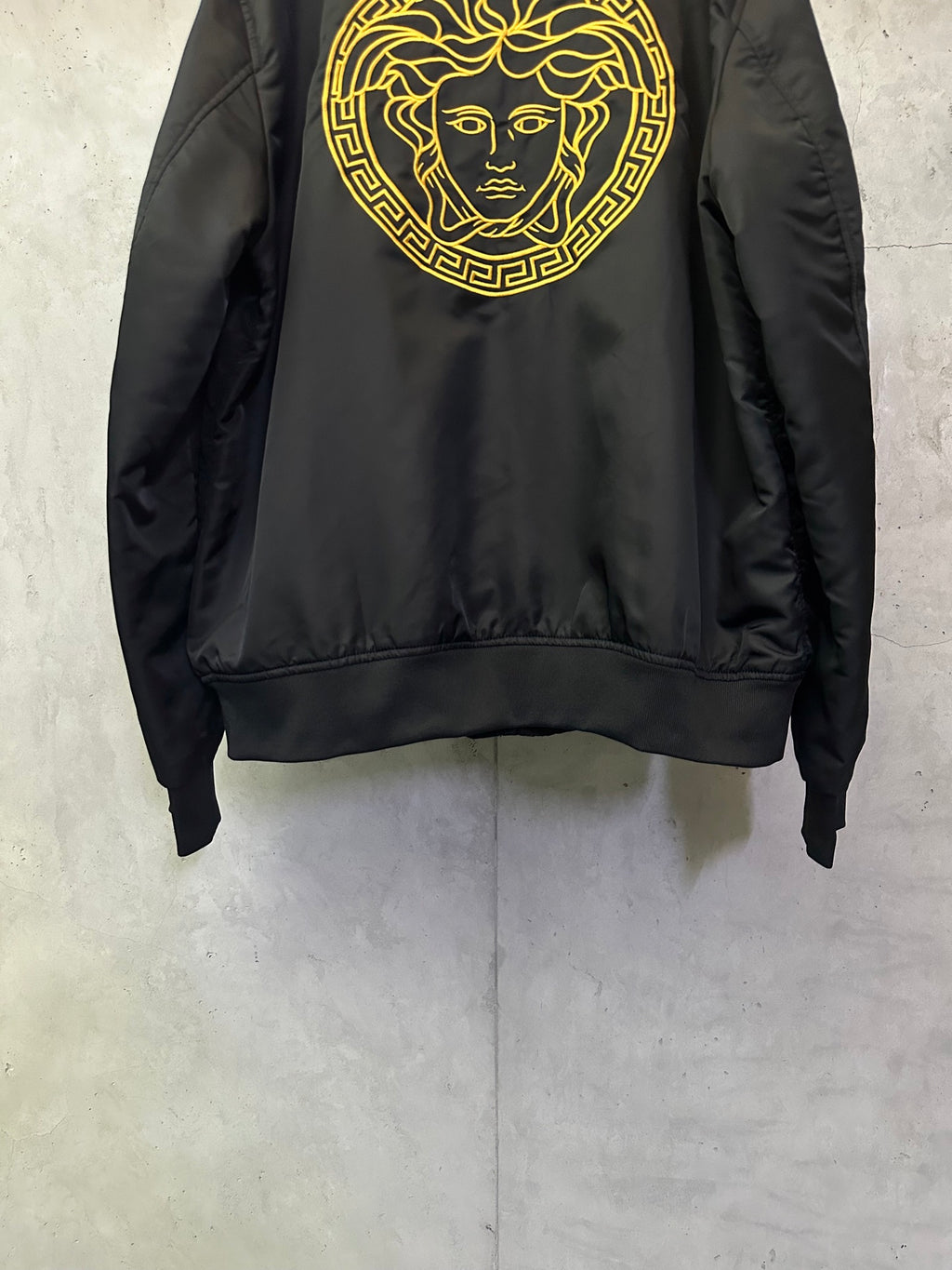 Black Versace bomber jacket with gold Medusa face emblem centered on back