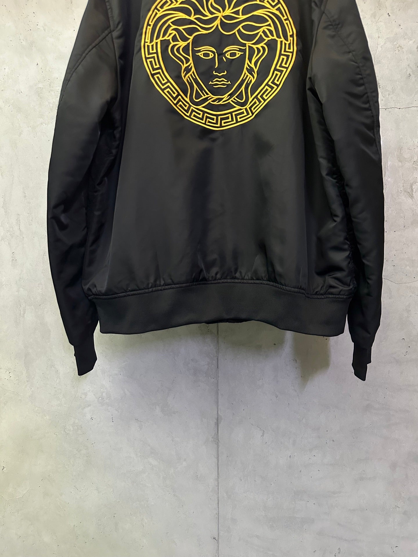 Black Versace bomber jacket with gold Medusa face emblem centered on back