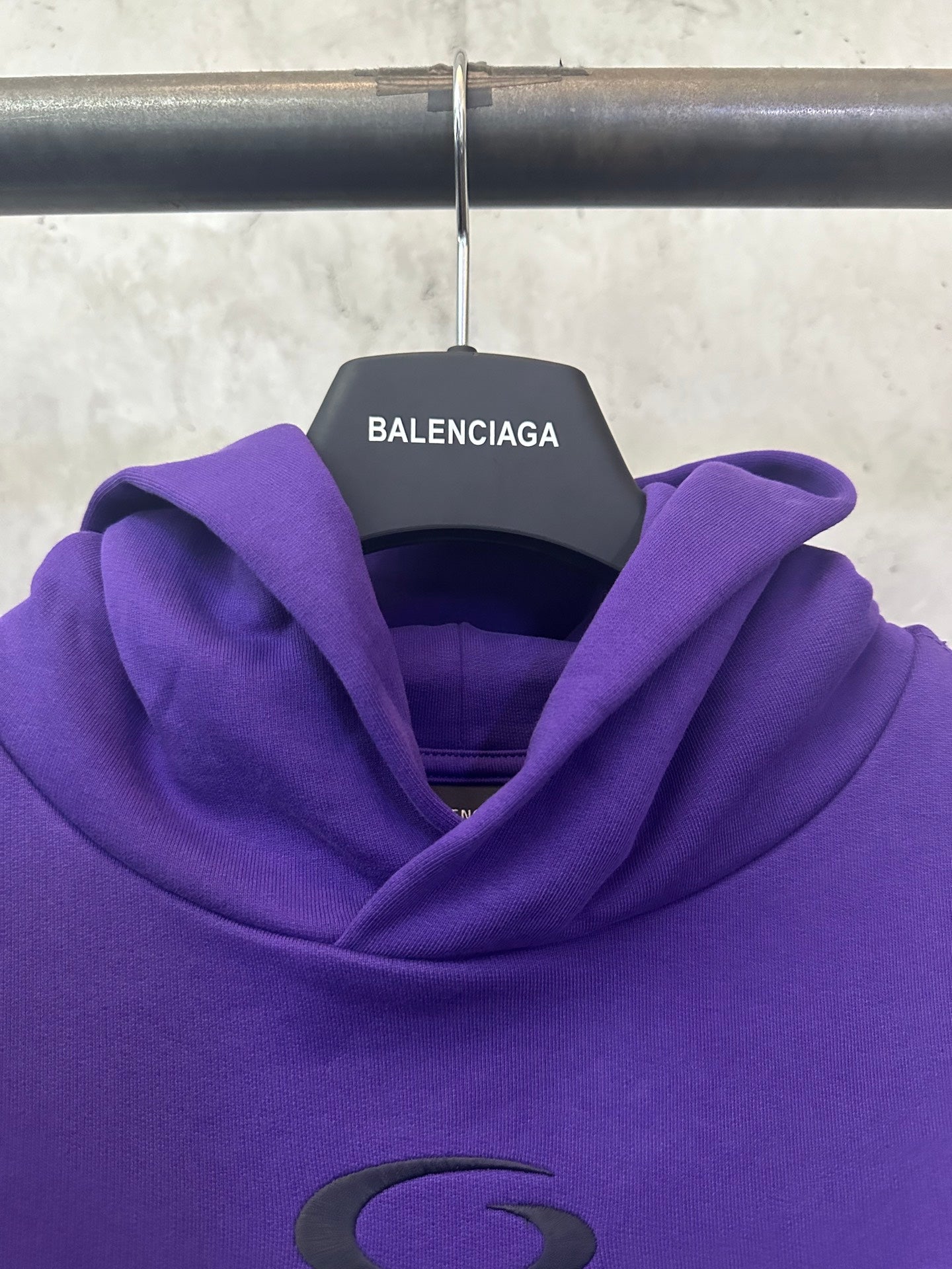 Purple Balenciaga hoodie hood close-up with small green oval emblem