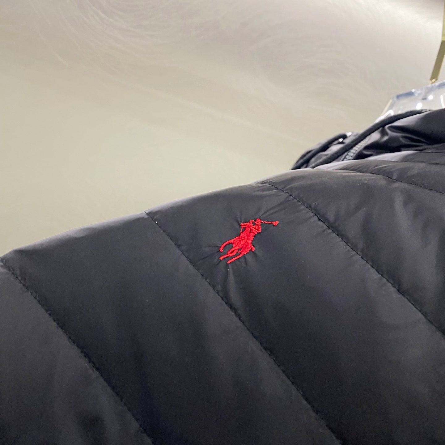 Navy quilted jacket with red embroidered logo on upper sleeve