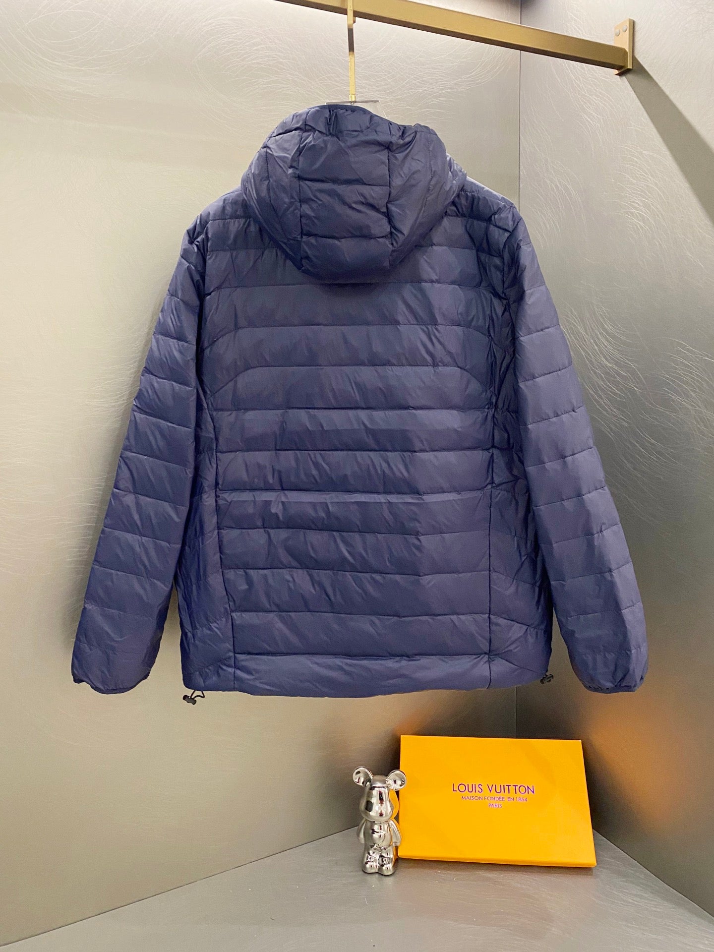 Blue quilted hooded jacket back view with full zip and drawstring hem
