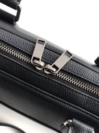 Black leather handbag with twin zippers and silver-tone buckles