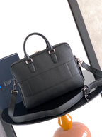 Black leather handbag with two top handles and shoulder strap attachment