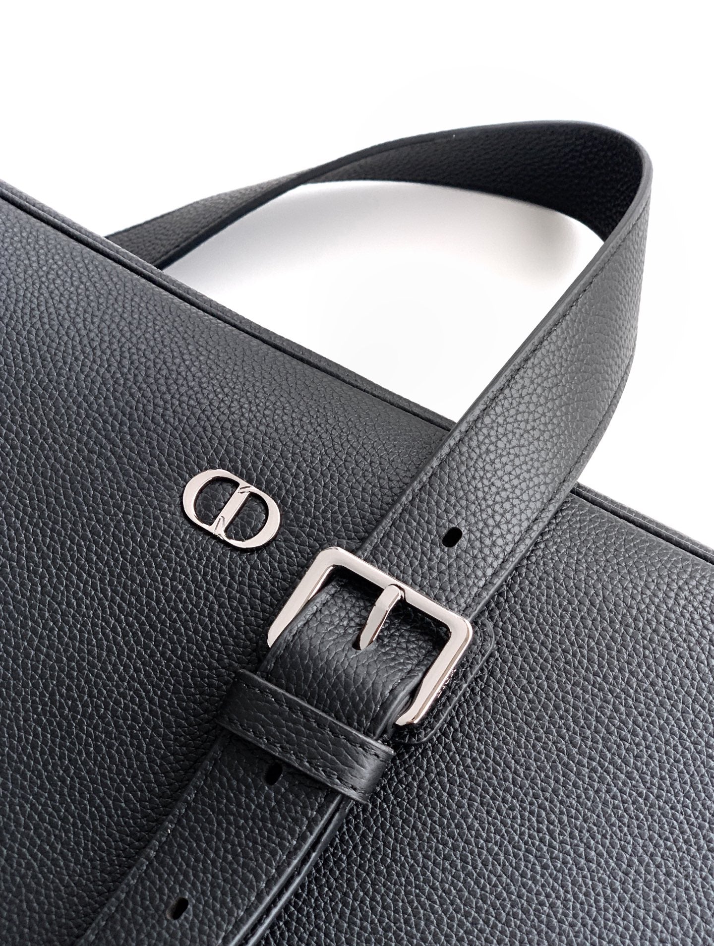 Black leather strap detail with engraved logo and buckle hardware