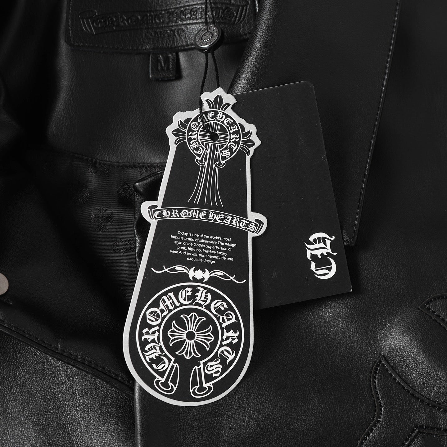 Black leather jacket with white hang tag attached near collar