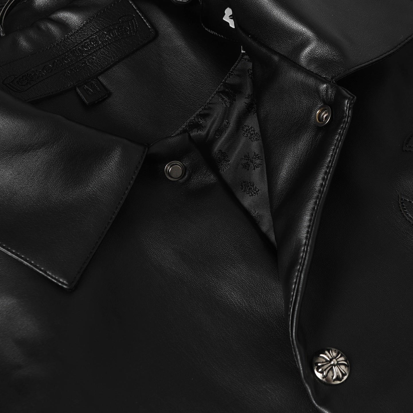 Black leather jacket front placket with snap buttons and floral embroidery