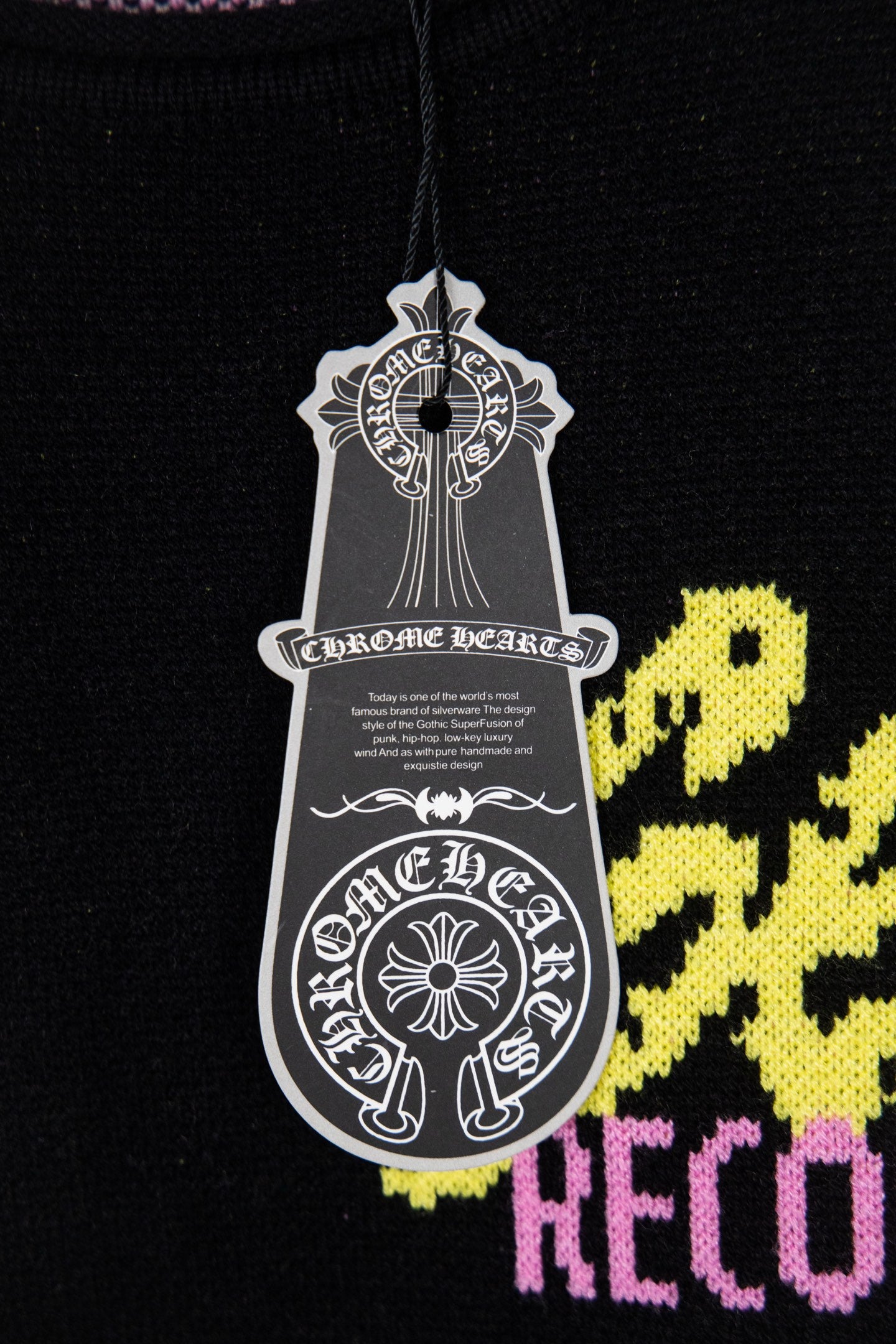 Black sweatshirt chest graphic with white crest tag and yellow plus pink accents
