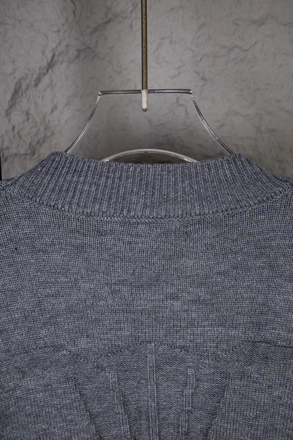 Gray knit sweater upper back with ribbed neckline and central seam