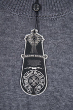 Gray knit sweater with hanging black logo tag at the neckline