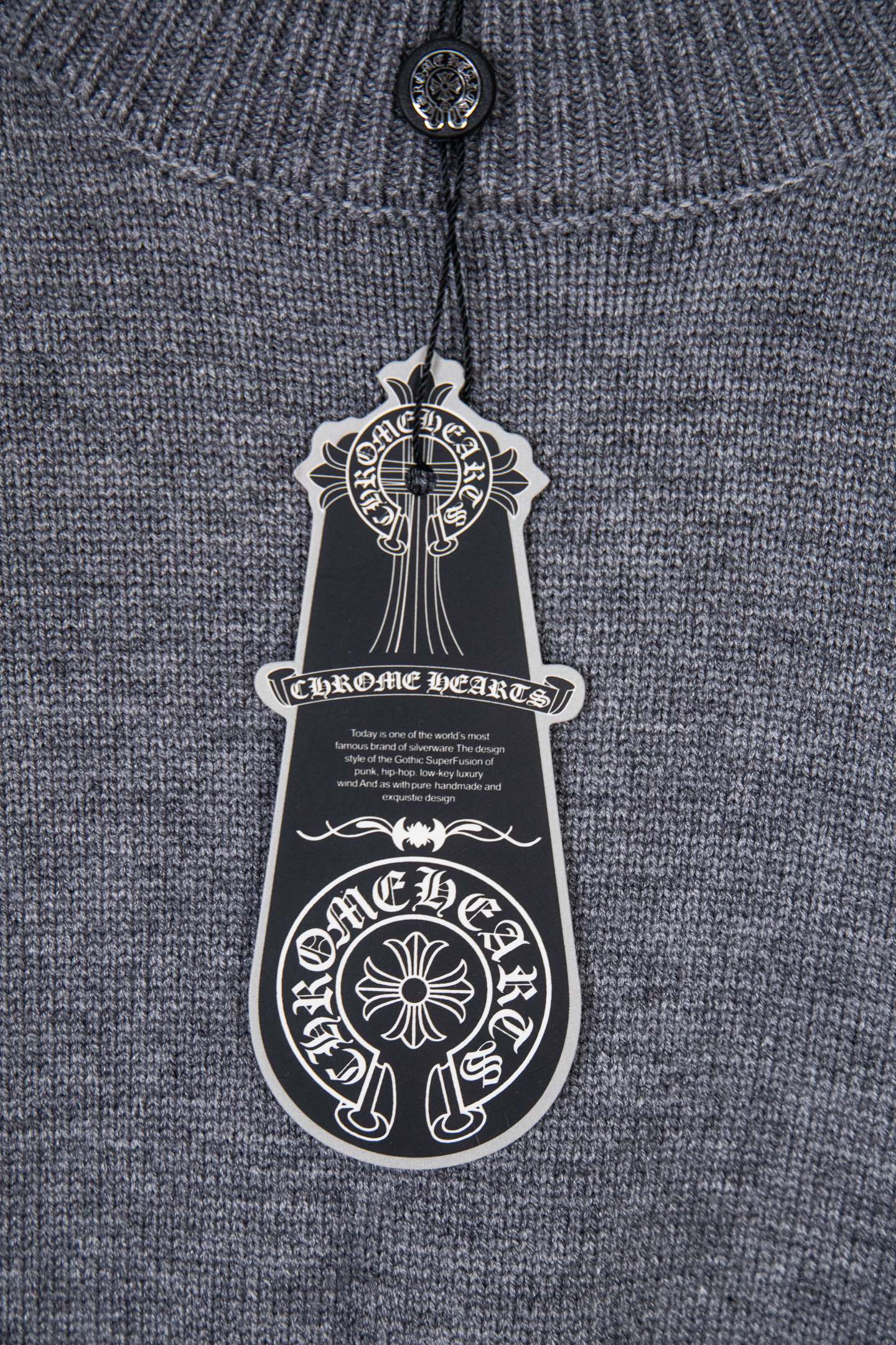 Gray knit sweater with hanging black logo tag at the neckline