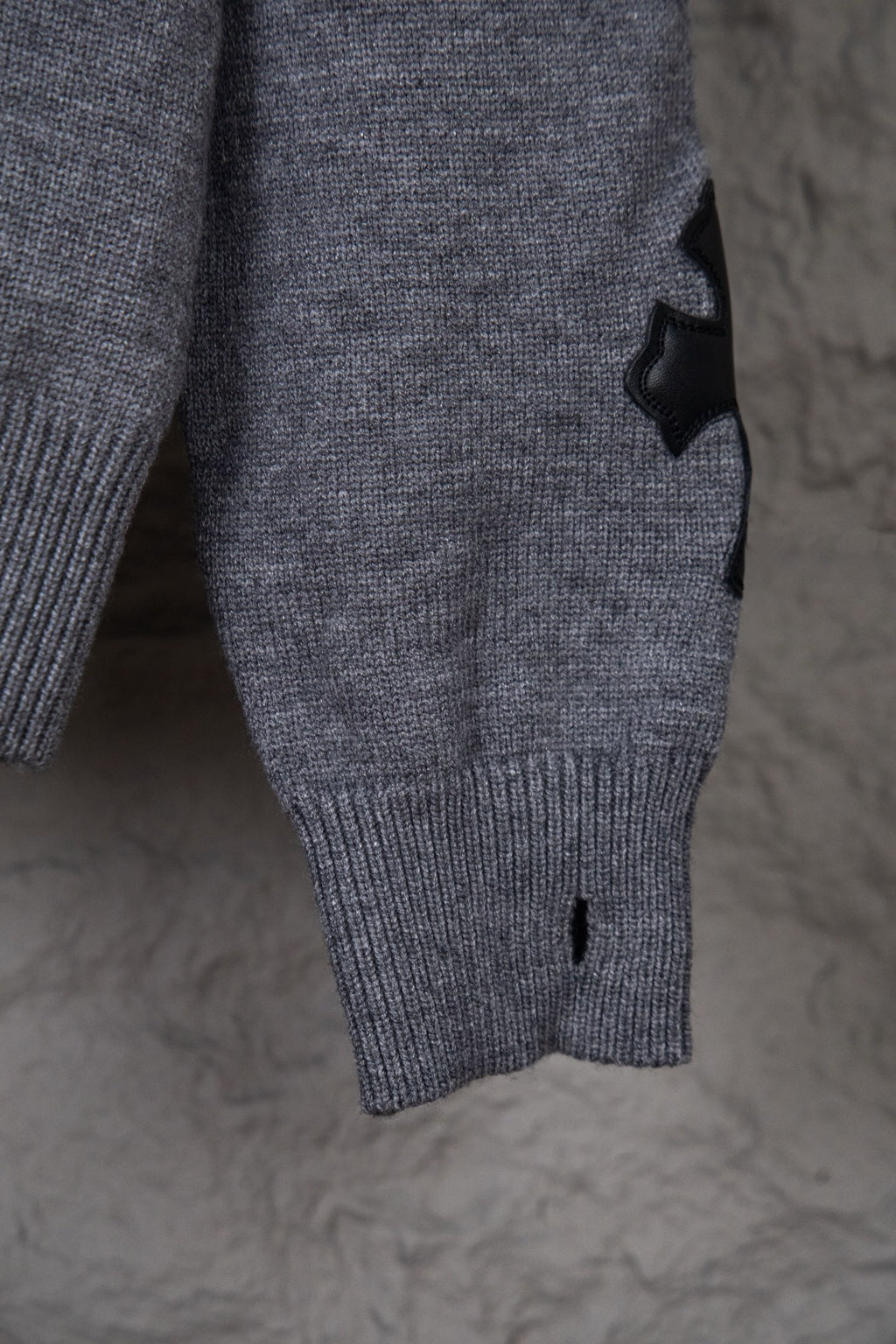 Gray knit sweater close-up of lower front with ribbed hem and small black detail