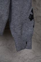Gray knit sweater close-up of lower front with ribbed hem and small black detail
