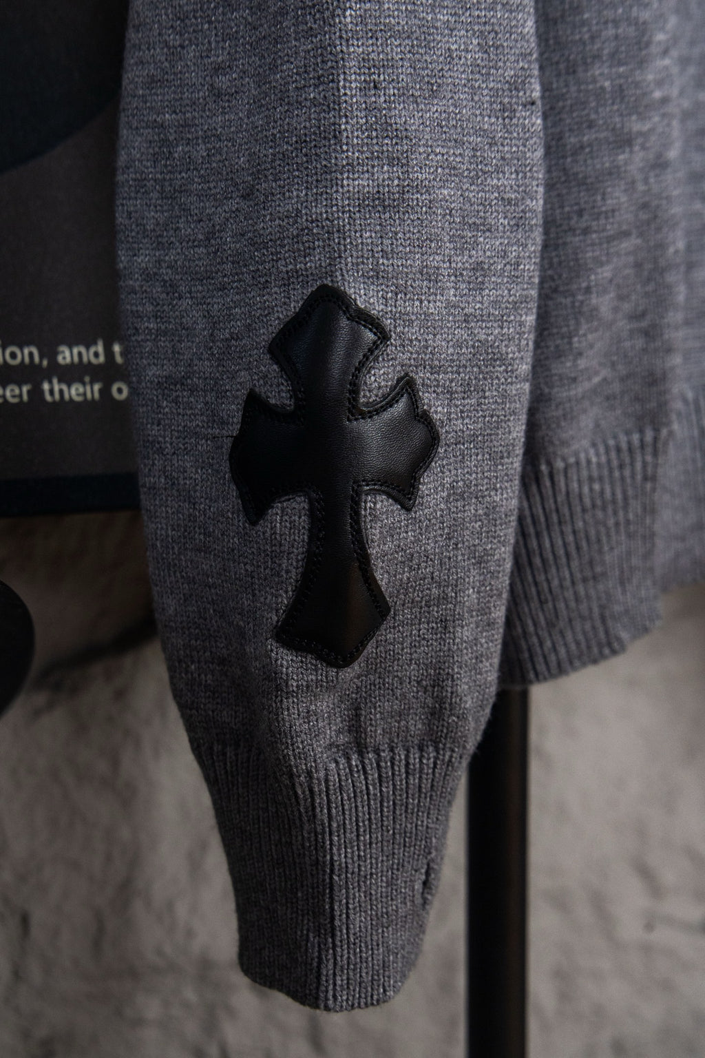 Gray knit sweater with black cross appliqué on front