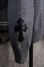 Gray knit sweater with black cross appliqué on front