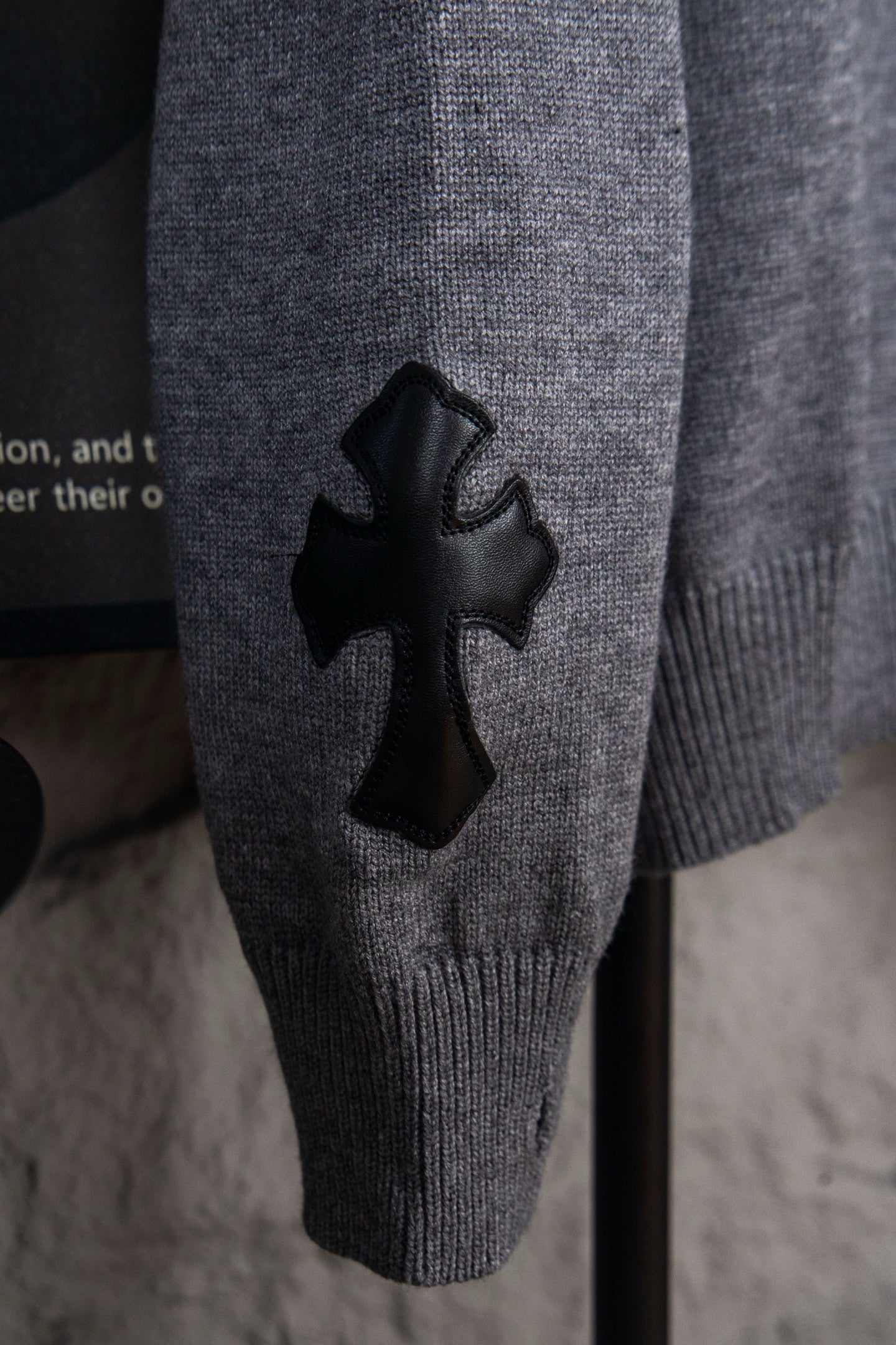 Gray knit sweater with black cross appliqué on front