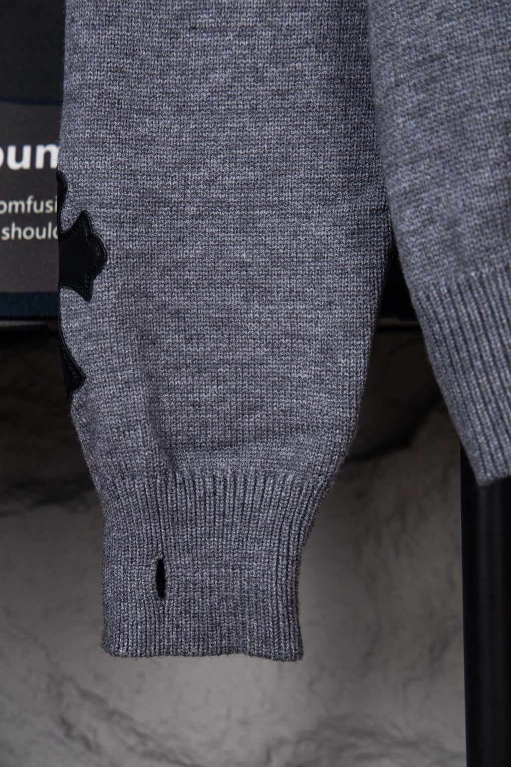 Gray knit sweater close-up of sleeve cuff and ribbed hem, small black detail