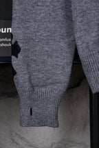 Gray knit sweater close-up of sleeve cuff and ribbed hem, small black detail