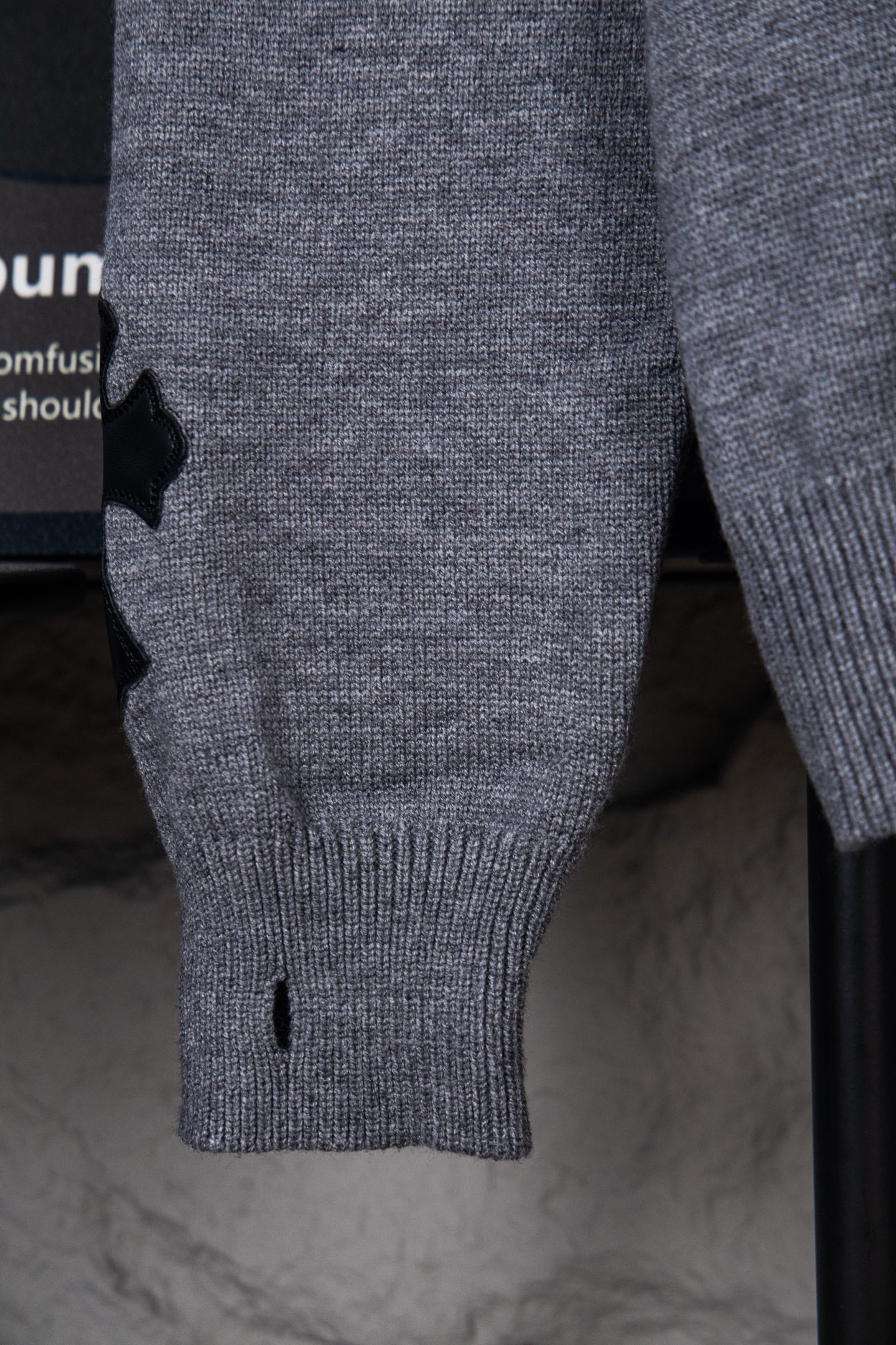 Gray knit sweater close-up of sleeve cuff and ribbed hem, small black detail