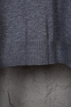 Gray knit sweater sleeve area with ribbed cuff and side seam visible