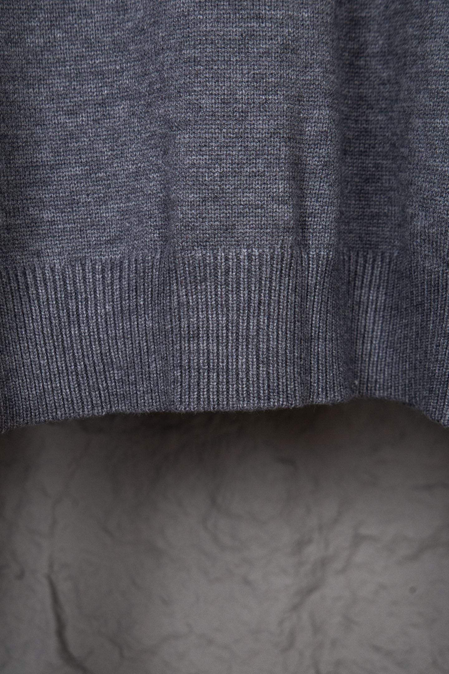 Gray knit sweater sleeve area with ribbed cuff and side seam visible