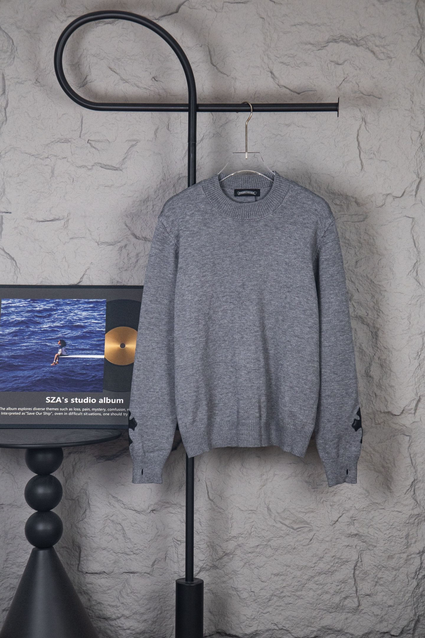 Gray long-sleeve knit sweater on hanger, crew neck and ribbed cuffs