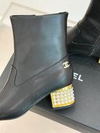 Black leather ankle boot with gold Chanel logo and jeweled block heel detail