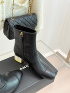 Black leather ankle boot pair on box, gold zipper details and jeweled block heels
