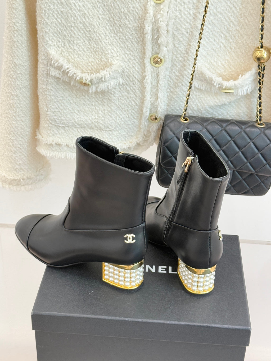 Black leather ankle boots on box, Chanel logo at side and jeweled heels