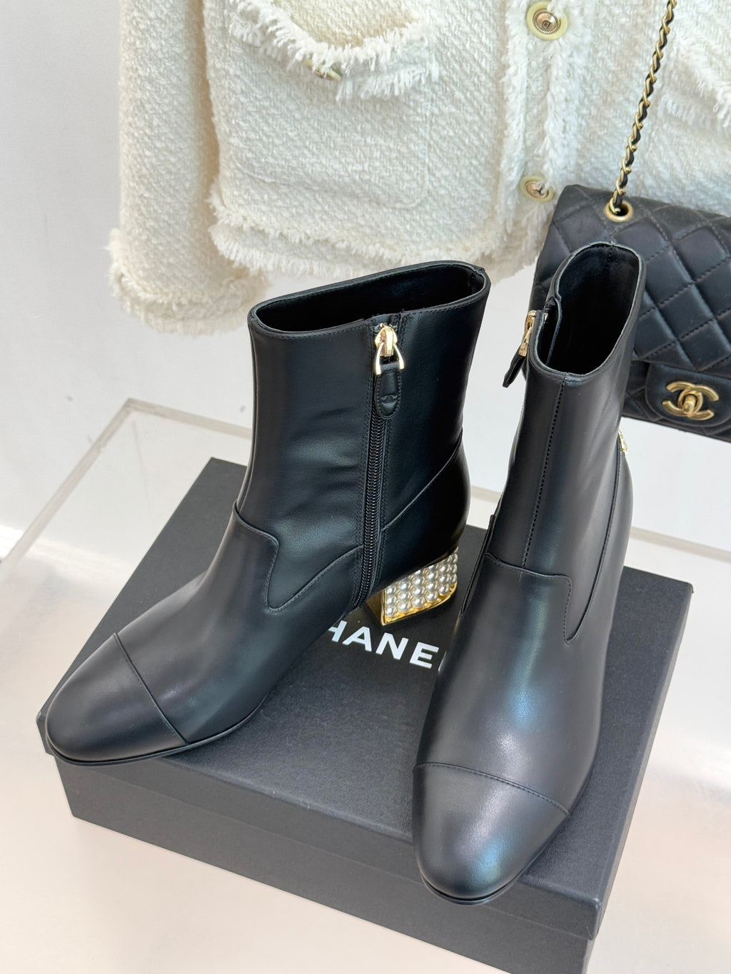 Black leather ankle boots with gold zipper pull and jeweled block heel, side view