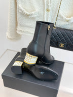 Black leather ankle boot on box with gold zipper, jeweled block heel and Chanel emblem