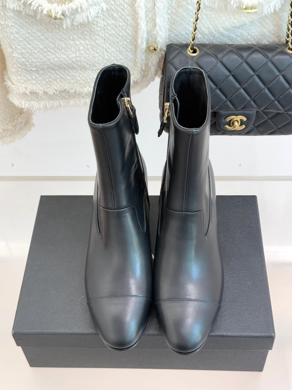Black leather ankle boots standing on box, tall shaft and jeweled heel trim