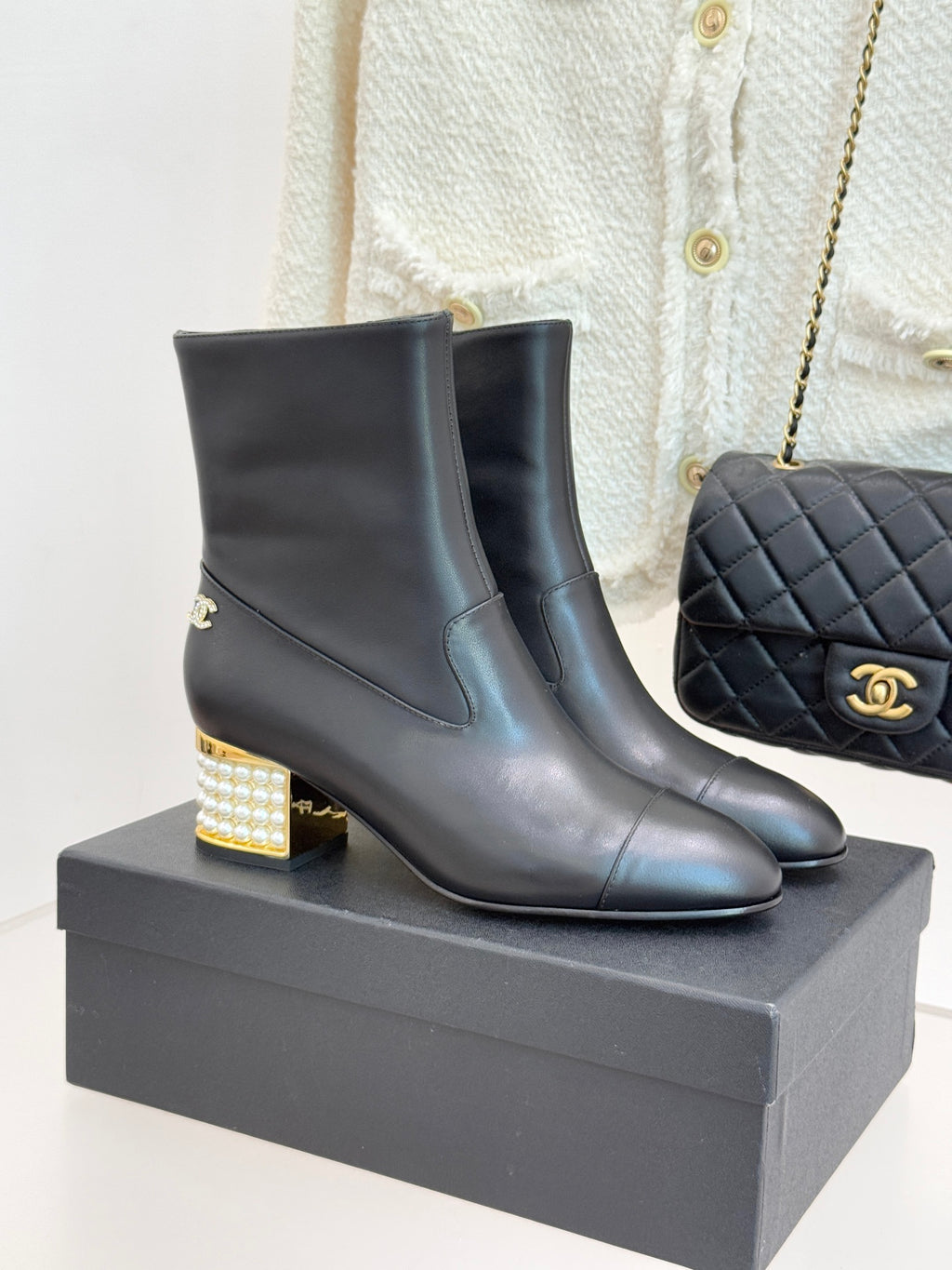 Black leather ankle boots with gold Chanel logo and jeweled block heel