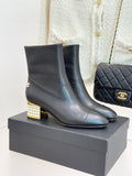Black leather ankle boots with gold Chanel logo and jeweled block heel