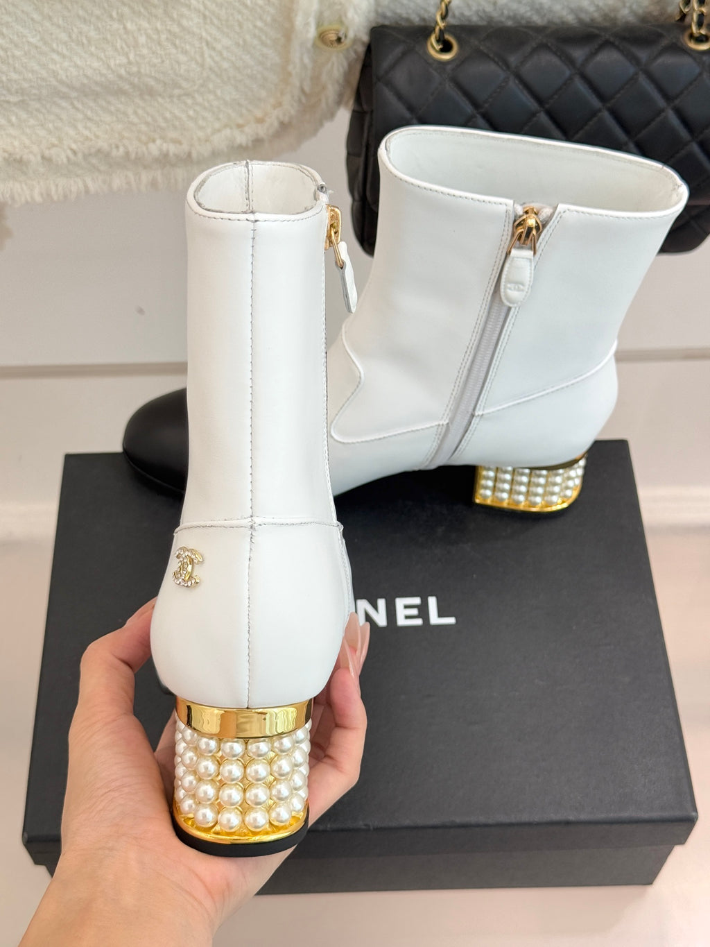 White ankle boots with gold studded heels, side zippers, on a box
