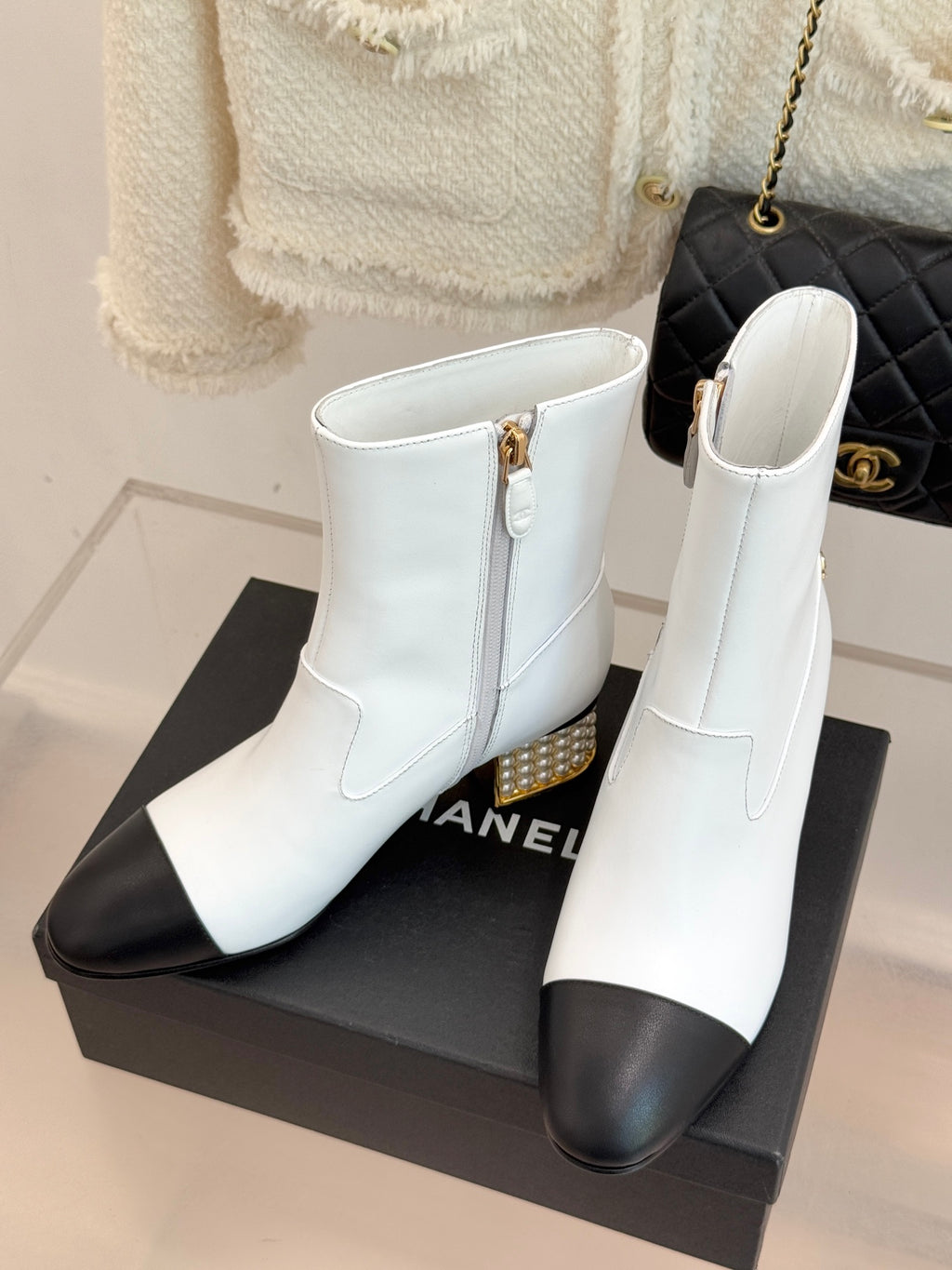 White ankle boots with black toe, side zipper, and gold studded heel