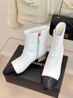 White ankle boots with black toe, side zipper, and gold studded heel