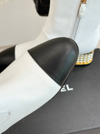 White ankle boot with black leather toe panel and gold-studded heel