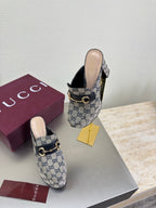 Gucci platform mules pair on display in blue GG canvas with gold horsebit hardware