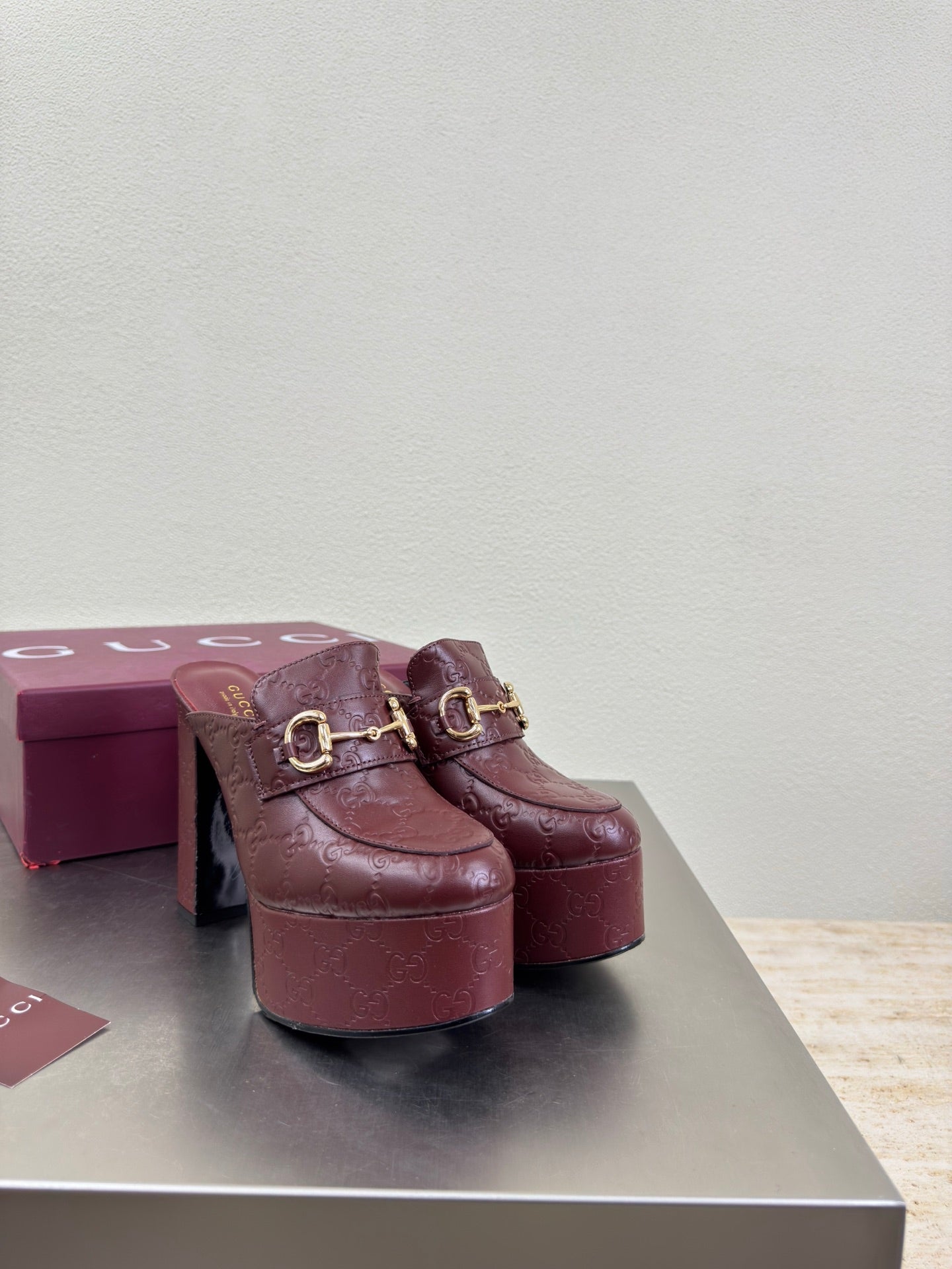 Burgundy Gucci platform mules with gold horsebit buckle, textured finish