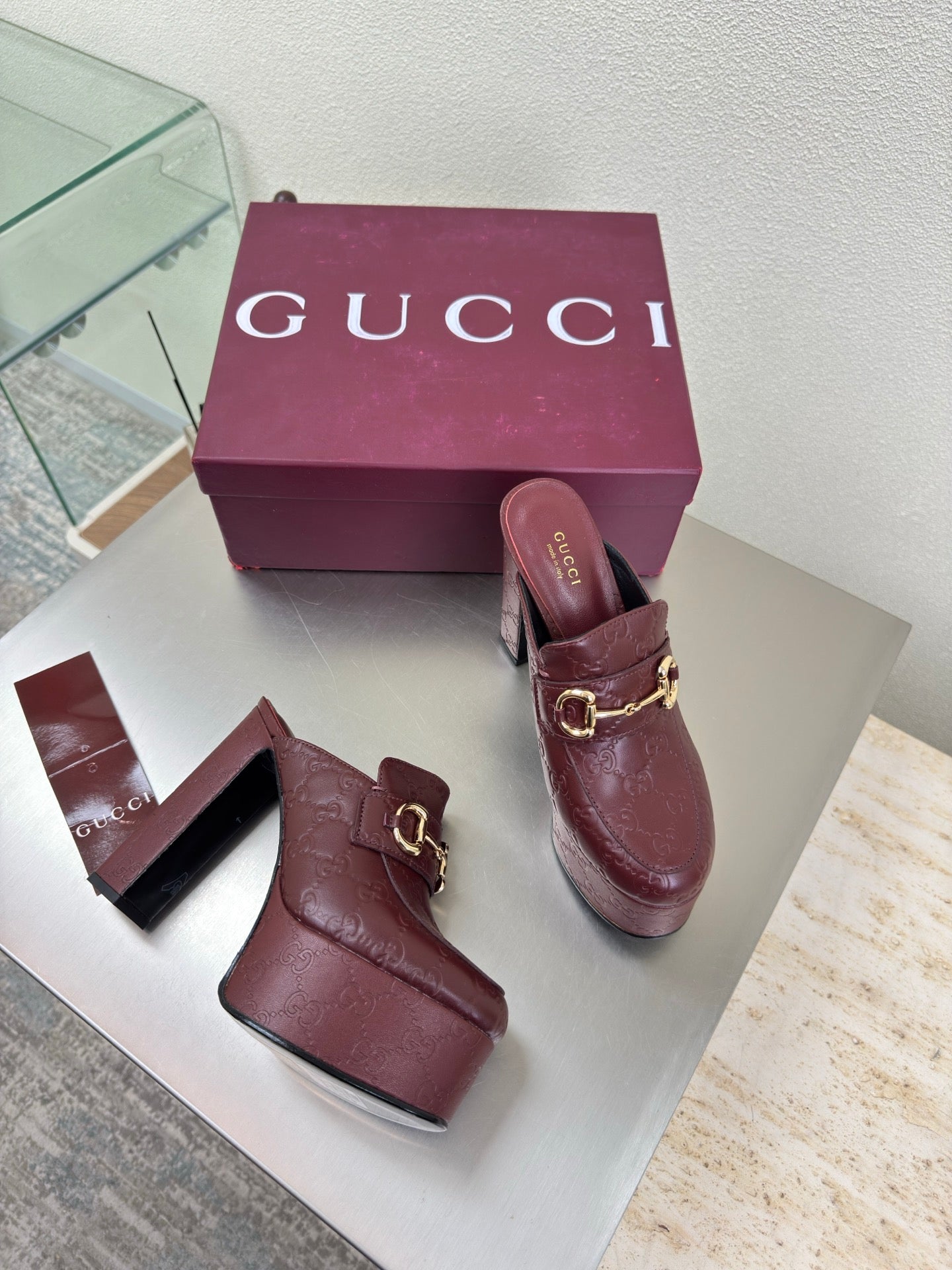 Burgundy Gucci platform mules with gold horsebit buckle, textured leather