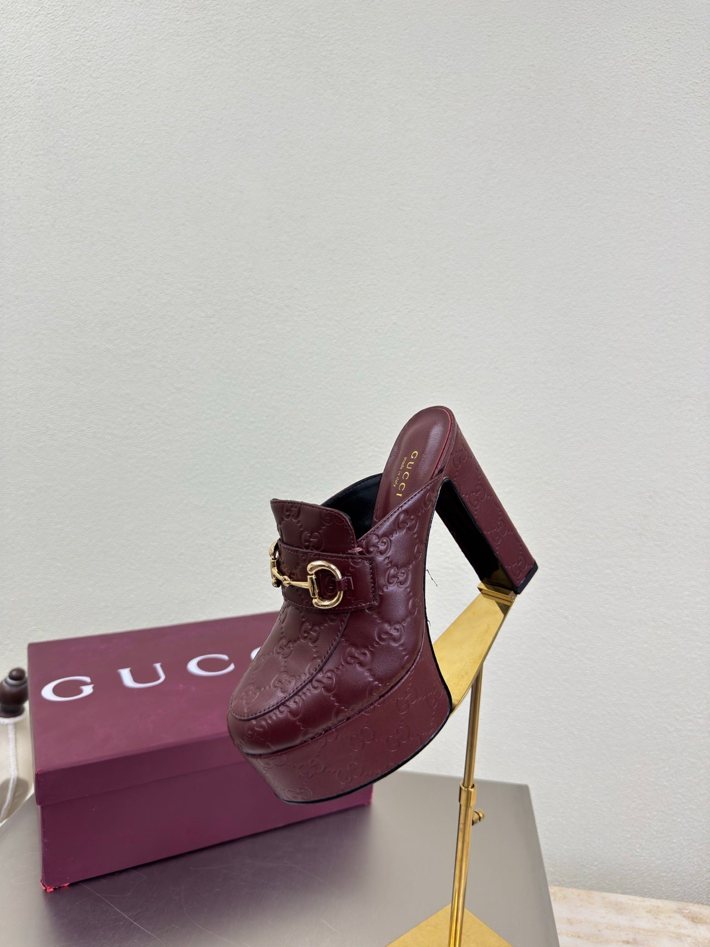 Burgundy Gucci mule with gold horsebit buckle and textured leather, side view