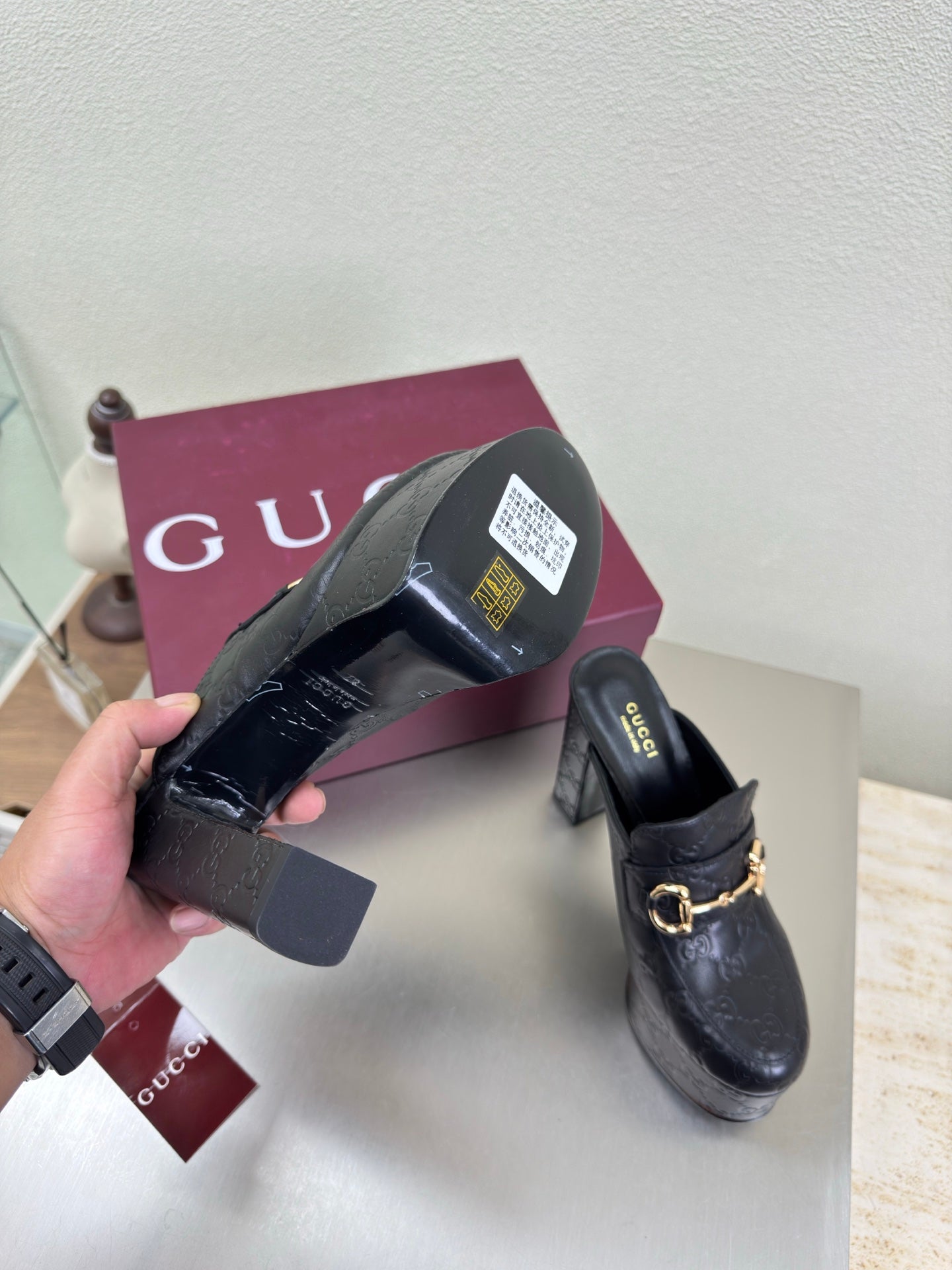 Black Gucci mule shown from heel with gold horsebit strap and textured leather